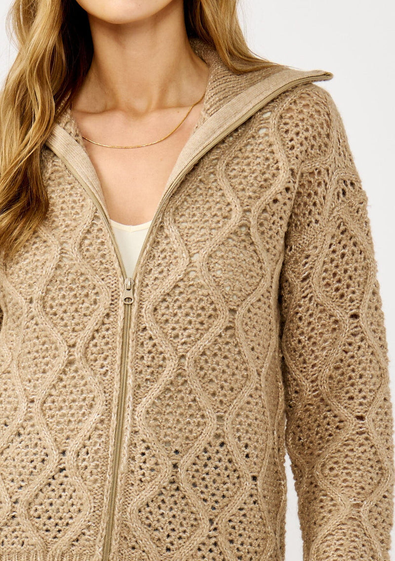 [Color: Mocha] A detail image of a blonde model wearing a brown cable knit sweater with a full-zip front, funnel neck, and ribbed trims. A classic fall layer to pair with denim. 