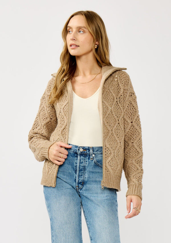 [Color: Mocha] A front facing image of a blonde model wearing a brown cable knit sweater with a full-zip front, funnel neck, and ribbed trims. A classic fall layer to pair with denim. 