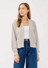 [Color: Heather Light Grey] A front facing image of a blonde model wearing a grey casual, lightweight cardigan with an open front, ribbed trim, and rolled edges. A classic staple cardigan for transitional styling. 