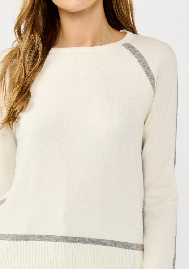 [Color: Cream/Heather Grey] A detail image of a blonde model wearing a cream pullover sweater with a grey border stripe. Featuring long cozy sleeves, a classic crew neckline, and ribbed trimming. 