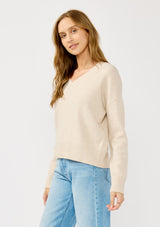 [Color: Heather Petal] A side facing image of a blonde model wearing a classic cozy v-neck pullover sweater with ribbed trims. Perfect for casual outings and the office. 