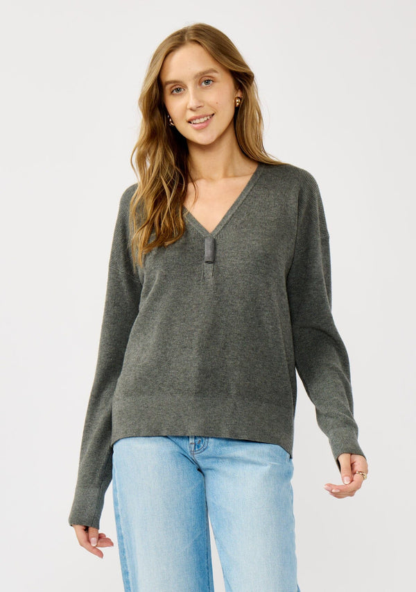 [Color: Heather Charcoal] A front facing image of a blonde model wearing a dark grey pullover sweater with a unique suede accent at the v-neckline. 