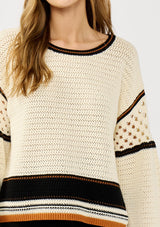 [Color: Natural/Black] A detail image of a blonde model wearing a cotton pointelle knit sweater with a border stripe. Featuring a classic crew neckline, dropped shoulders, and open knit details along the sleeves. 