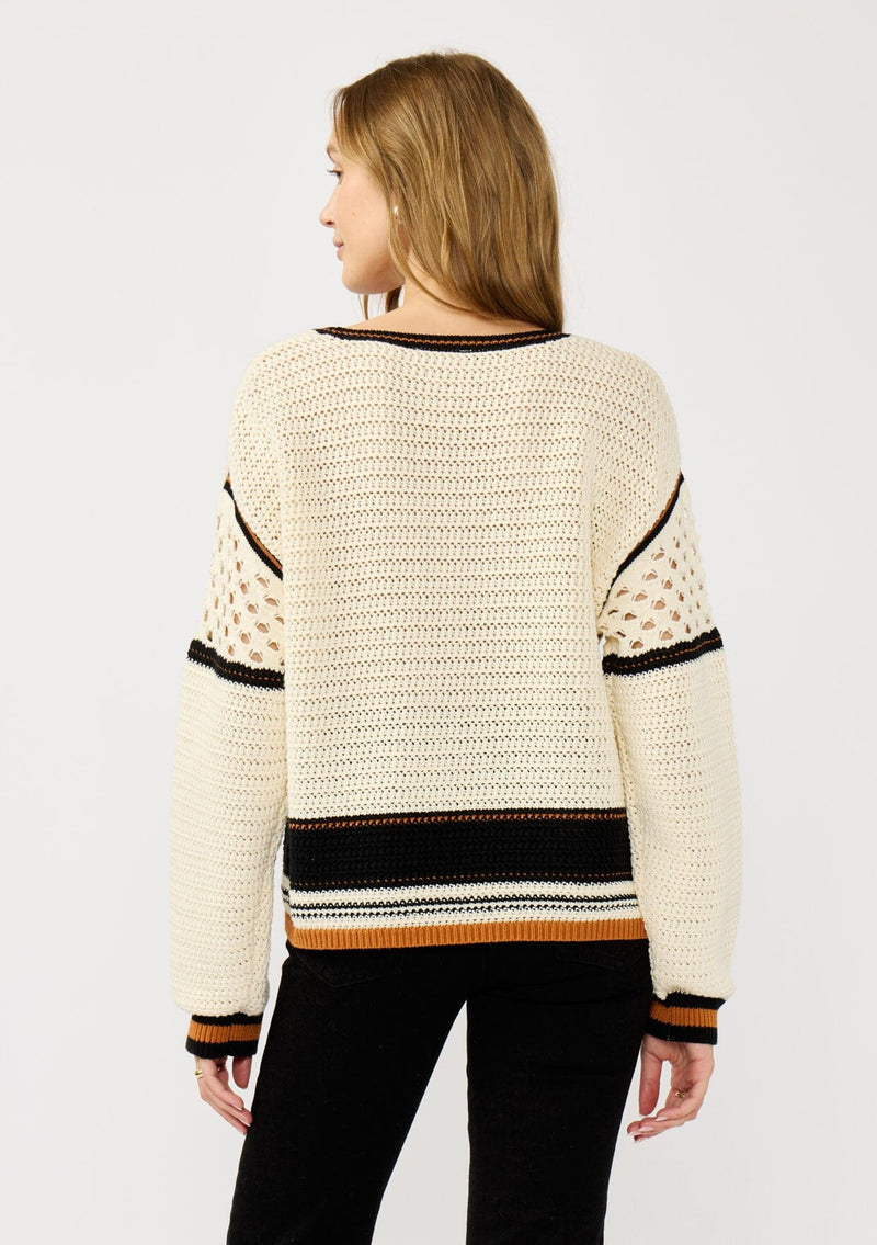 [Color: Natural/Black] A back facing image of a blonde model wearing a cotton pointelle knit sweater with a border stripe. Featuring a classic crew neckline, dropped shoulders, and open knit details along the sleeves. 