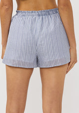[Color: Blue/White] A back facing image of a brunette model wearing a blue and white striped short with an elastic drawstring waist and side pockets.