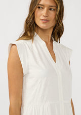 [Color: White] A detail image f a brunette model earing a white baby doll mini dress an eyelet design, split v-neckline, button front, and rolled cap sleeves. 