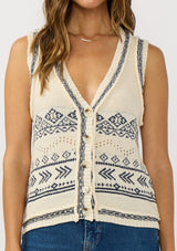 [Color: Natural/Navy] A detail image of a brunette model wearing a jacquard knit vest with a v-neckline and button front. 