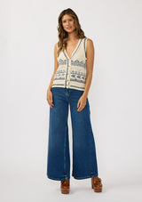 [Color: Natural/Navy] A front facing image of a brunette model wearing a jacquard knit vest with a v-neckline and button front. 
