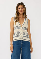[Color: Natural/Navy] A front facing image of a brunette model wearing a jacquard knit vest with a v-neckline and button front. 
