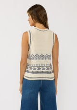 [Color: Natural/Navy] A back facing image of a brunette model wearing a jacquard knit vest with a v-neckline and button front. 