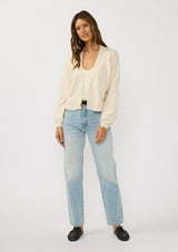 [Color: Ivory] A front facing image of a brunette model wearing an ivory cardigan with a collarless design, floral embroidery, and rib trims. 