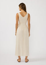 [Color: Natural] A back facing image of a brunette model wearing a beige jacquard midi dress with a smocked bodice, v-neckline, adjustable waist belt, and side pockets. 