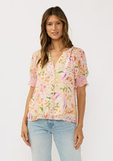 [Color: Natural/Fuchsia] A front facing image of a brunette model wearing a pink floral top with a button front and puff sleeves with smocked cuffs. A pretty spring casual top paired with denim. 