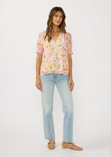 [Color: Natural/Fuchsia] A front facing image of a brunette model wearing a pink floral top with a button front and puff sleeves with smocked cuffs. A pretty spring casual top paired with denim. 