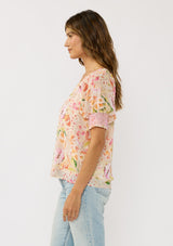 [Color: Natural/Fuchsia] A front facing image of a brunette model wearing a pink floral top with a button front and puff sleeves with smocked cuffs. A pretty spring casual top paired with denim. 