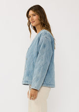 [Color: Blue] A side facing image of a brunette model wearing a blue quilted denim jacket with a button front, dropped shoulders, and side pockets. Fully lined for effortless comfort. 