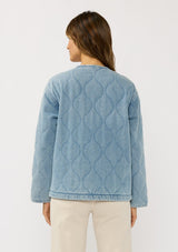 [Color: Blue] A back facing image of a brunette model wearing a blue quilted denim jacket with a button front, dropped shoulders, and side pockets. Fully lined for effortless comfort. 