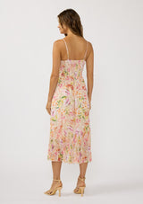 [Color: Natural/Fuchsia] A back facing image of brunette model wearing a pink floral midi dress with adjustable spaghetti straps, a smocked back, and a pleated hem detail. 