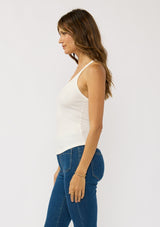 [Color: White] A side facing image of a brunette model wearing a white micro ribbed tank top with a v-neckline and racerback. A basic everyday tank top.