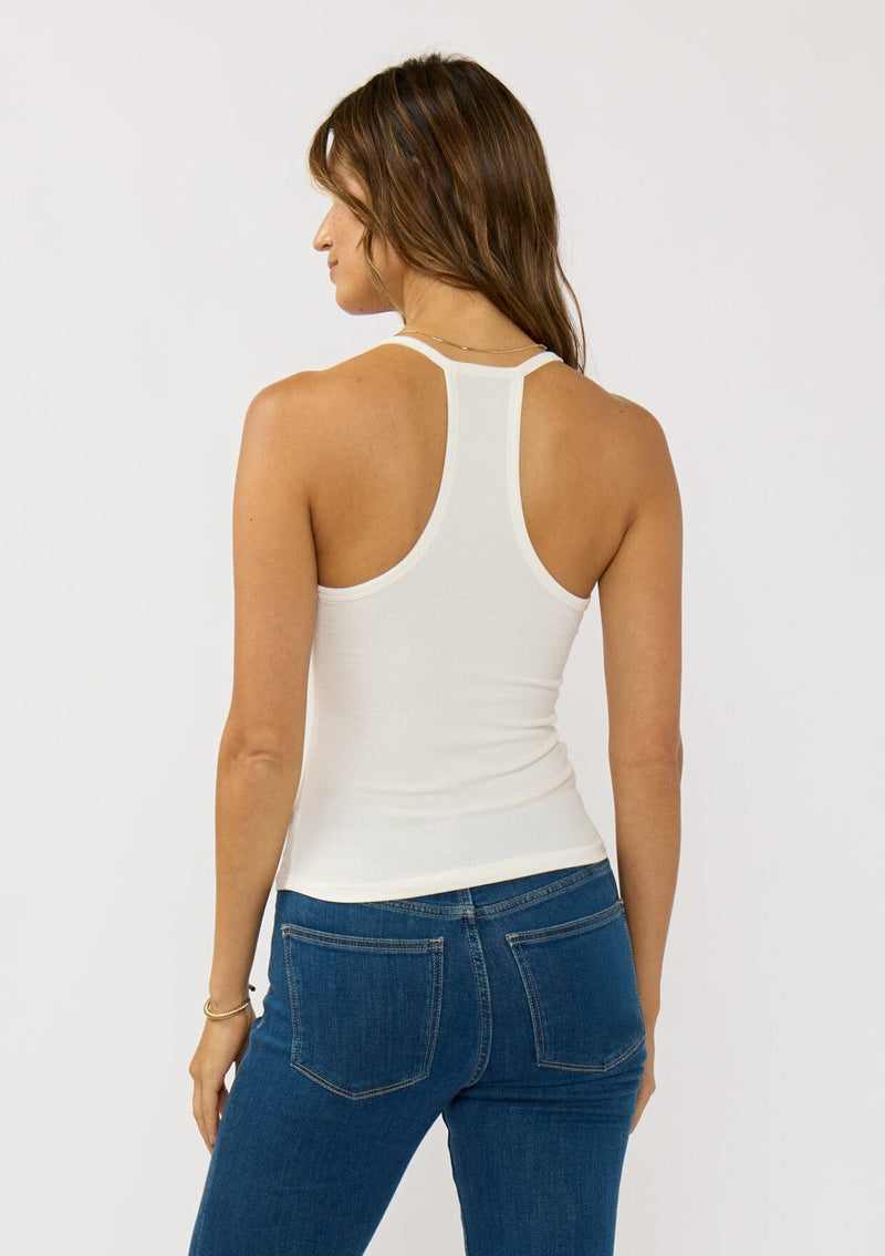 [Color: White] A back facing image of a brunette model wearing a white micro ribbed tank top with a v-neckline and racerback. A basic everyday tank top.