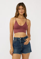 [Color: Burgundy] A front facing image of a brunette model wearing a basic burgundy bralette cami with a slim stretchy fit and a v-neckline. 