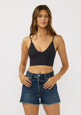 [Color: Black] A front facing image of a brunette model wearing a basic black bralette cami with a slim stretchy fit and a v-neckline. 