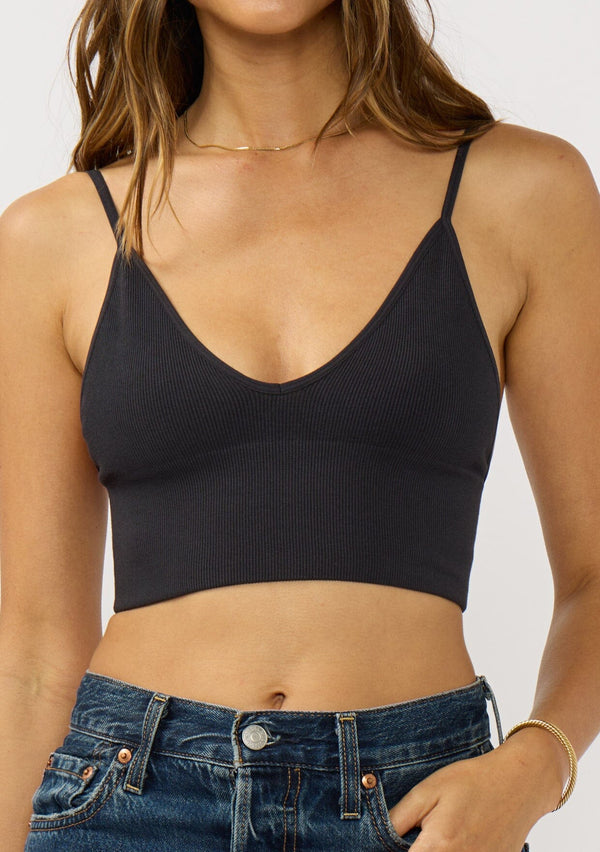 [Color: Black] A front facing image of a brunette model wearing a basic black bralette cami with a slim stretchy fit and a v-neckline. 