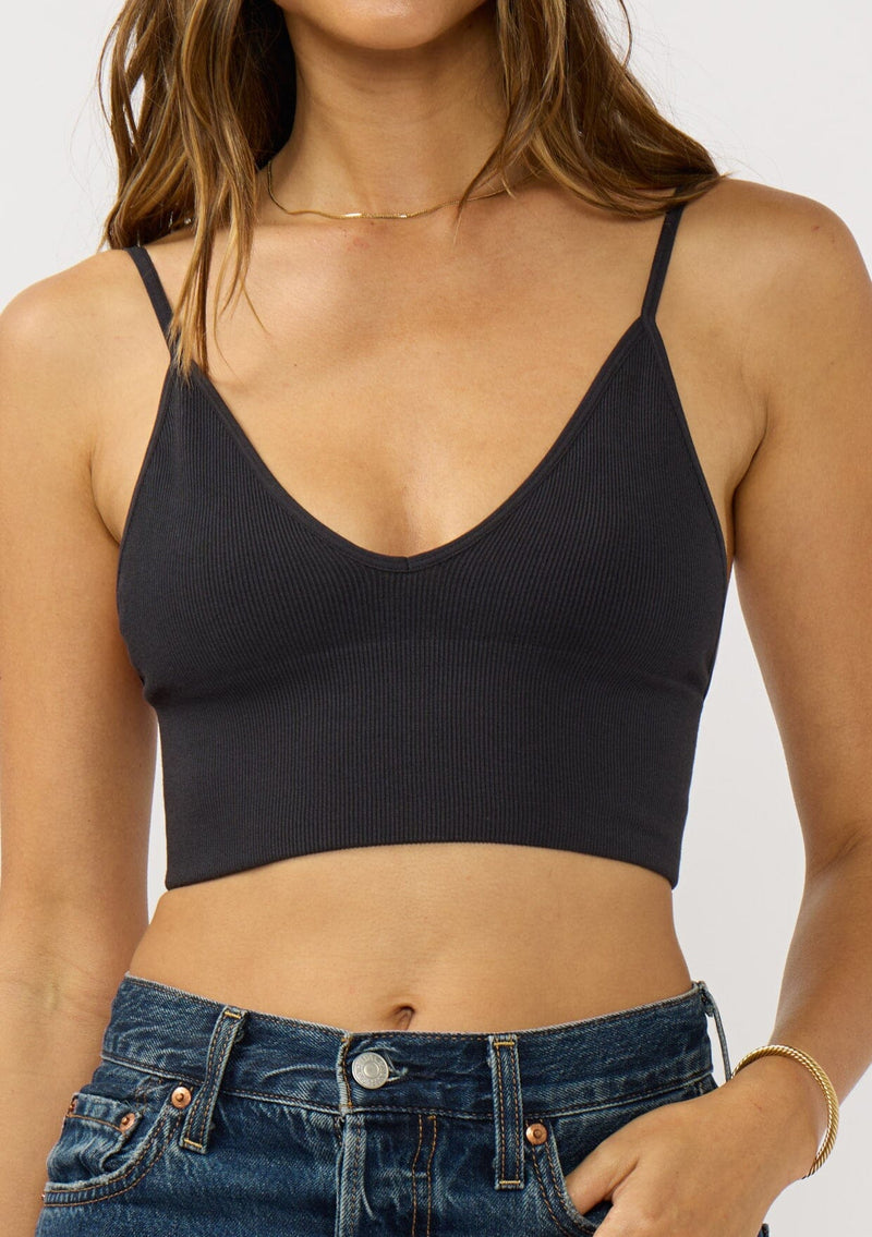 [Color: Black] A front facing image of a brunette model wearing a basic black bralette cami with a slim stretchy fit and a v-neckline. 