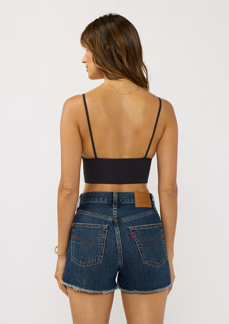 [Color: Black] A back facing image of a brunette model wearing a basic black bralette cami with a slim stretchy fit and a v-neckline. 