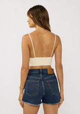 [Color: Cream] A back facing image of a brunette model wearing a basic off white bralette cami with a slim stretchy fit and a v-neckline.