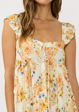 [Color: Ivory/Coral] A detail image of a brunette model wearing an orange floral maxi dress with an elastic shoulder strap, ruffle sleeves, a sweetheart neckline with tie detail, and a flowy tiered skirt. A flowy casual spring dress. 