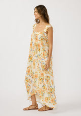 [Color: Ivory/Coral] A side facing image of a brunette model wearing an orange floral maxi dress with an elastic shoulder strap, ruffle sleeves, a sweetheart neckline with tie detail, and a flowy tiered skirt. A flowy casual spring dress. 