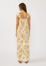 [Color: Ivory/Coral] A back facing image of a brunette model wearing an orange floral maxi dress with an elastic shoulder strap, ruffle sleeves, a sweetheart neckline with tie detail, and a flowy tiered skirt. A flowy casual spring dress. 