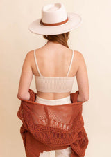 [Color: Oatmeal] A back facing image of a model wearing a rib knit crop top in beige. Featuring a v neckline, spaghetti straps, and a body hugging silhouette. A soft and cozy top crafted in stretchy fabric, perfect for layering or wearing on its own. 