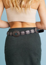 [Color: Black] A back facing image of a black boho belt with silver medallions and a turquoise accents. 