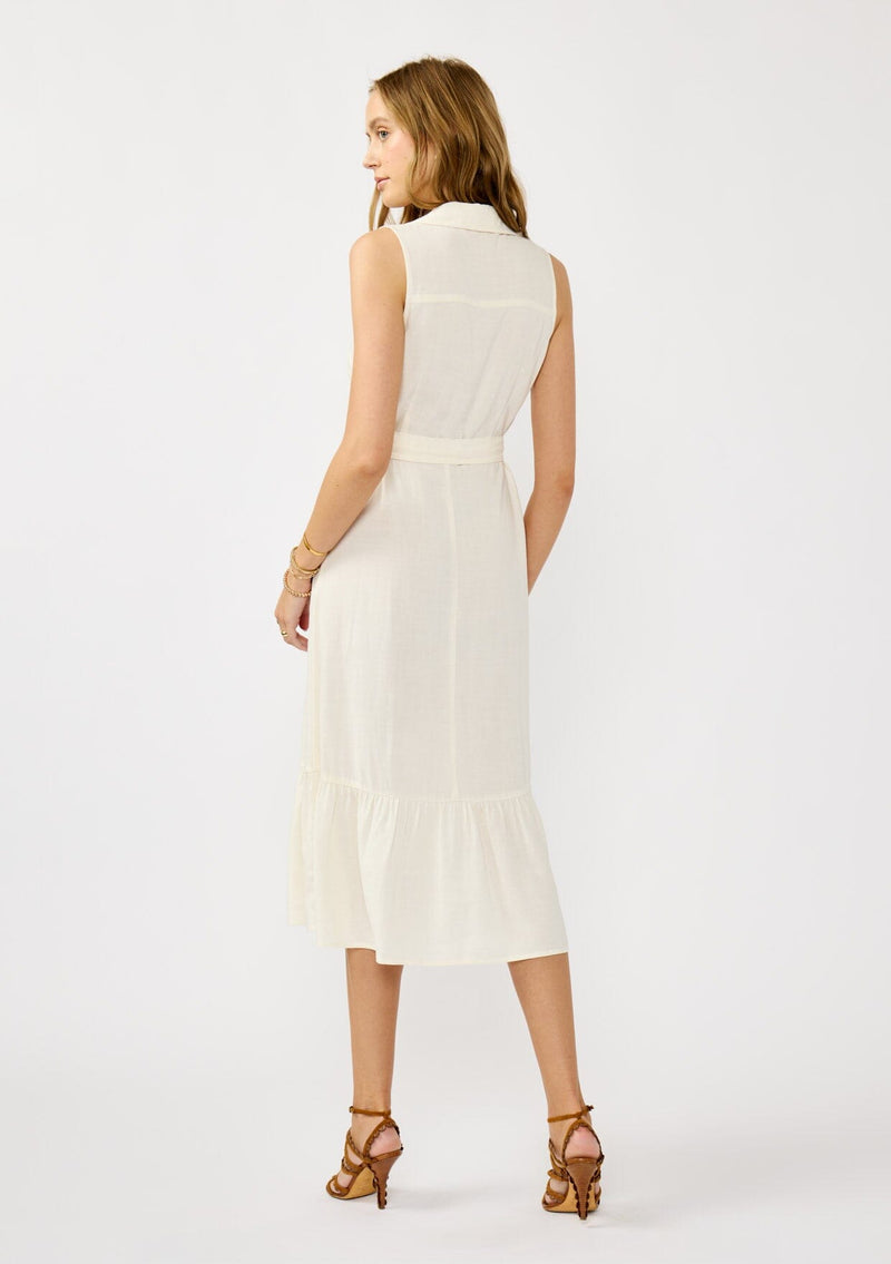 [Color: Natural] A back facing image of a blonde model wearing an off white sleeveless shirt dress with a collared neckline, button front, and a self tie waist belt. 
