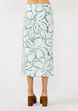 [Color: Ivory/Dark Teal] A back facing image of a blonde model wearing a white and teal tropical floral print wrap skirt, tie waist, and a smocked back. Styled with a matching tie front top. Perfect for vacation or casual outings. 