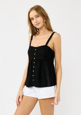 [Color: Black] A front facing image of a blonde model wearing a black boho tank top with a smocked back, button front, an eyelet trim, and pintuck details. Perfect for everyday warm weather styling. 