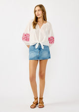 [Color: Off White/Fuchsia] A front-facing image of a blonde model wearing a white sheer tie-front top, featuring delicate pink floral embroidered cutouts along the sleeves.