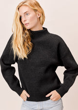 [Color: Charcoal] A blonde model wearing a charcoal sweater with an elegant funnel neck, a concealed zip closure at the back neck, and contrast ribbed details. A basic cold weather sweater for the fall season. 