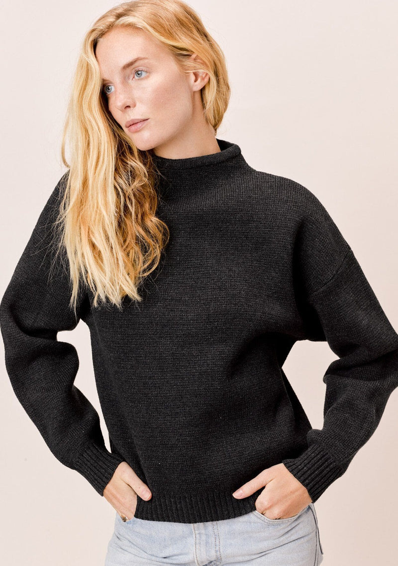 [Color: Charcoal] A blonde model wearing a charcoal sweater with an elegant funnel neck, a concealed zip closure at the back neck, and contrast ribbed details. A basic cold weather sweater for the fall season. 