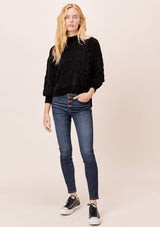 [Color: Black] A blonde model wearing a cozy cable knit sweater made with super soft chenille. Featuring a flattering ribbed funnel neck and a chic high low hemline with side vents. 
