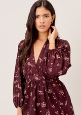 [Color: Merlot Rose] A romantic, vintage inspired floral mini dress. Featuring a v neckline, a waist defining tie back detail, and voluminous long sleeves.