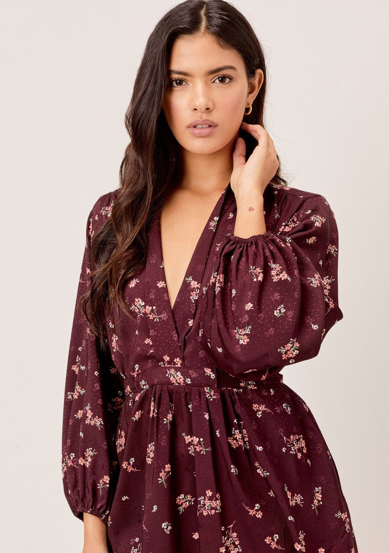 [Color: Merlot Rose] A romantic, vintage inspired floral mini dress. Featuring a v neckline, a waist defining tie back detail, and voluminous long sleeves.