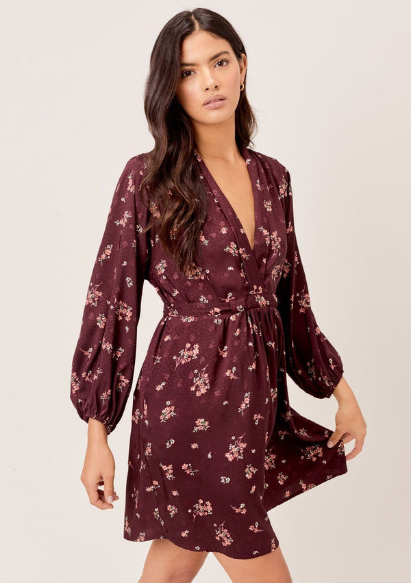 [Color: Merlot Rose] A romantic, vintage inspired floral mini dress. Featuring a v neckline, a waist defining tie back detail, and voluminous long sleeves.