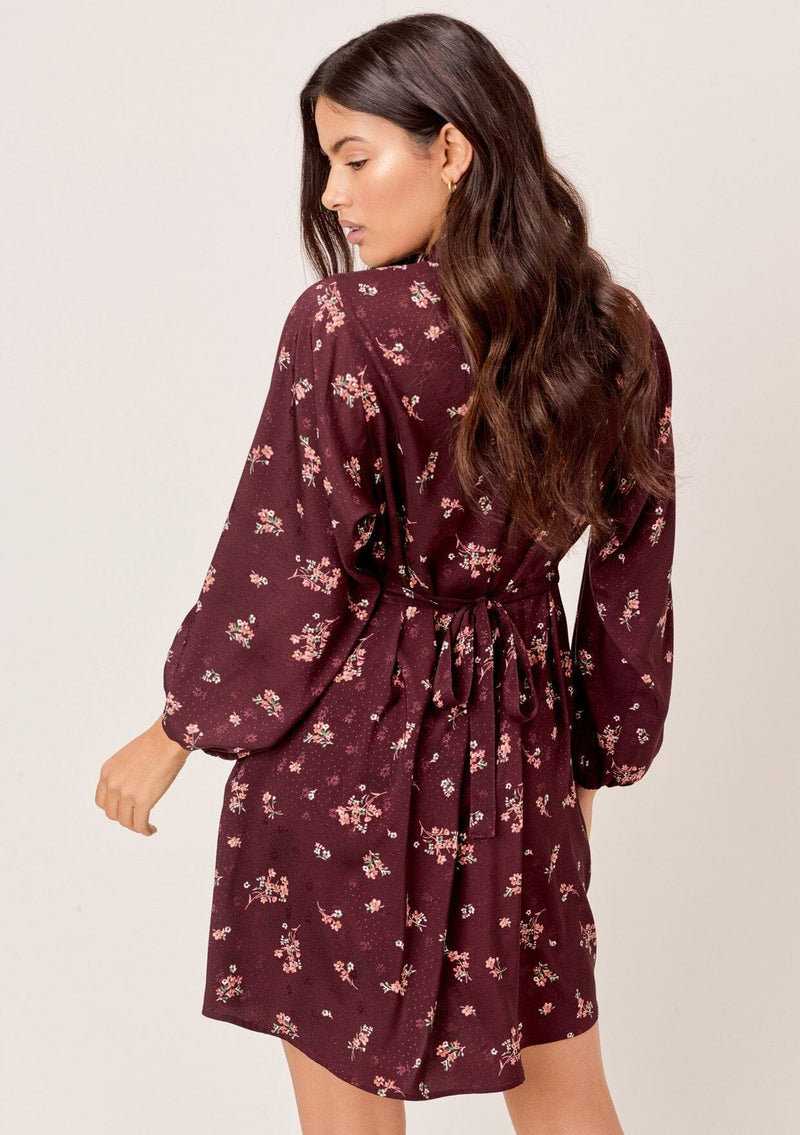 [Color: Merlot Rose] A romantic, vintage inspired floral mini dress. Featuring a v neckline, a waist defining tie back detail, and voluminous long sleeves.