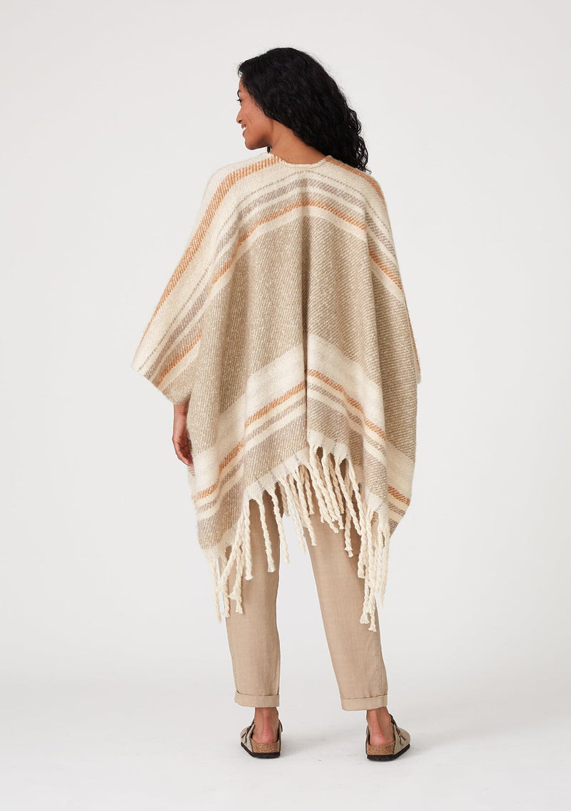 [Color: Taupe/Rust] A back facing image of a brunette model wearing a soft sweater shawl in a taupe and cream stripe. With a fringed hemline, a mid length silhouette, an open front, and long sleeves. 