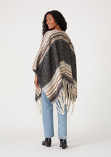 [Color: Navy/Taupe] A back facing image of a brunette model wearing a soft sweater shawl in a navy blue and taupe stripe. With a fringed hemline, a mid length silhouette, an open front, and long sleeves. 