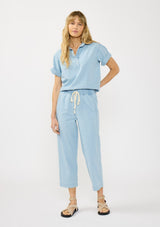 [Color: Light Denim Blue] A front facing image of a blonde model wearing a casual light blue cropped pant with an elastic waistband, drawstring, and side pockets. Styled with a matching short sleeve collared shirt. 