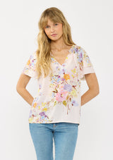 [Color: Blush/Dusty Blue] A front facing image of a blonde model wearing a pink floral top with layered short sleeves and a split v-neckline. A spring feminine top for casual outings. 